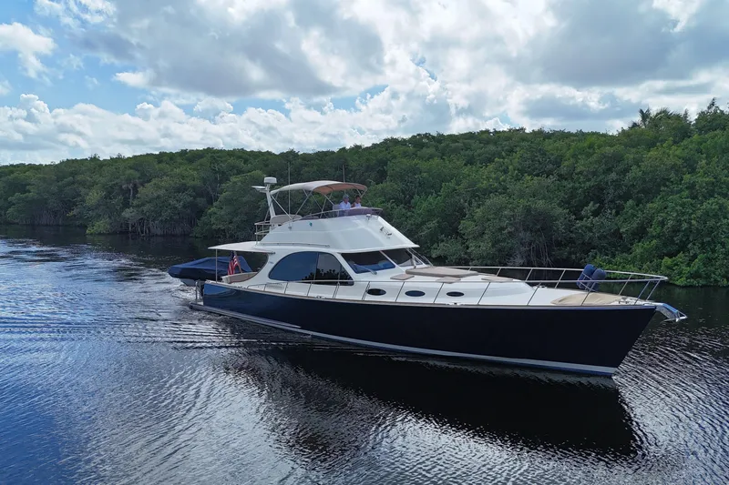 Tutto Bene Yacht Photos Pics 2018 Palm Beach Motor Yachts PB55 Flybridge cruising on a serene river with lush greenery.