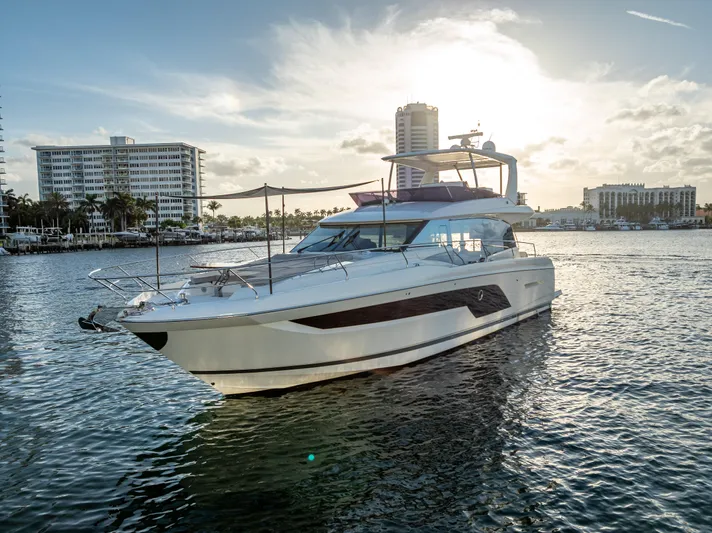  Yacht Photos Pics 2023 Prestige 590 yacht on water at sunset, with cityscape in background.