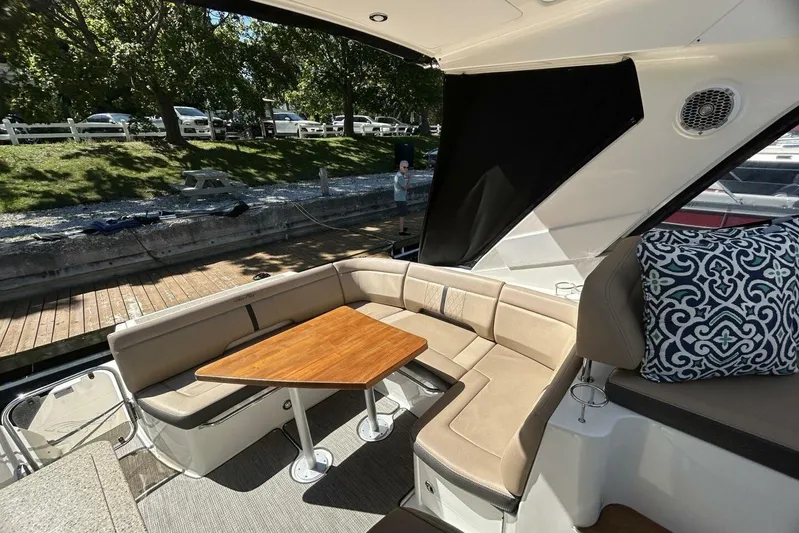  Yacht Photos Pics 2016 Sea Ray 350 Sundancer interior with beige seating, wooden table, and decorative pillow.