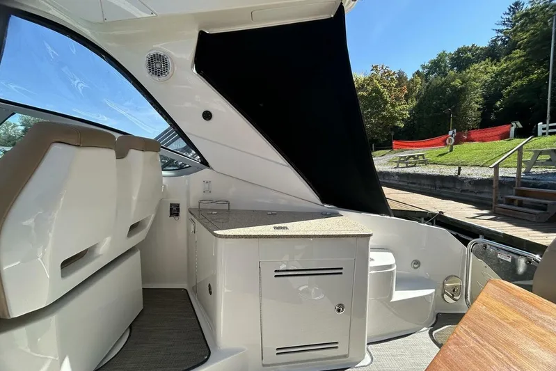  Yacht Photos Pics 2016 Sea Ray 350 Sundancer interior with seating and kitchenette, docked near greenery.