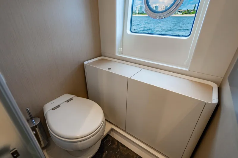 Effortless Yacht Photos Pics 2023 Azimut Fly 68 yacht bathroom with modern design, featuring a toilet and window view.