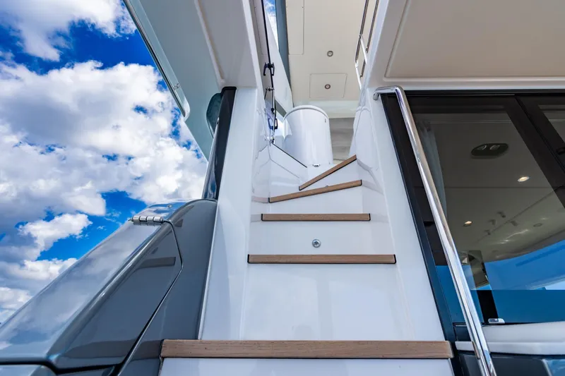 Effortless Yacht Photos Pics Staircase on 2023 Azimut Fly 68 yacht against a bright blue sky with clouds.