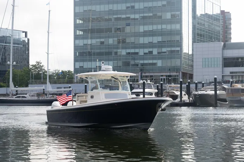 Malihini Yacht Photos Pics 2019 Hunt Yachts 32 Center Console in marina, cityscape background, American flag displayed.
