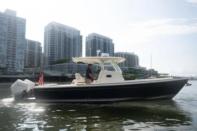 Malihini Yacht Photos Pics 2019 Hunt Yachts 32 Center Console cruising near urban waterfront buildings.