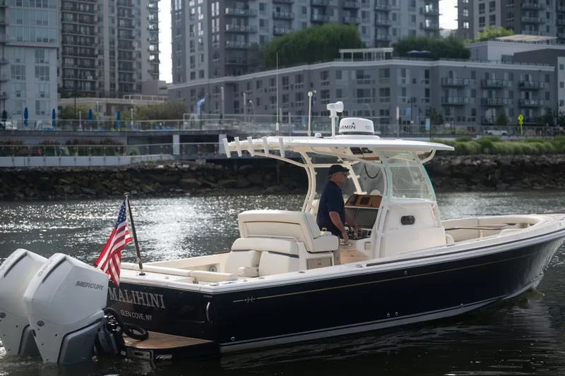 Malihini Yacht Photos Pics 2019 Hunt Yachts 32 Center Console boat on urban waterway, American flag displayed.