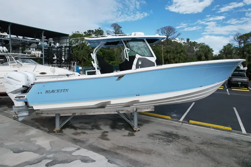  Yacht Photos Pics 2023 Blackfin 332 CC boat in light blue, displayed on a stand at a marina.