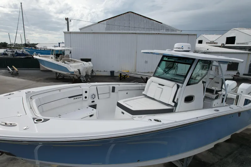  Yacht Photos Pics 2023 Blackfin 332 CC boat with sleek design, docked near industrial buildings.