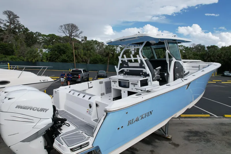  Yacht Photos Pics 2023 Blackfin 332 CC boat with Mercury engine, parked outdoors under a cloudy sky.