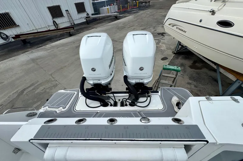  Yacht Photos Pics 2023 Blackfin 332 CC boat with dual outboard engines, docked beside another vessel.
