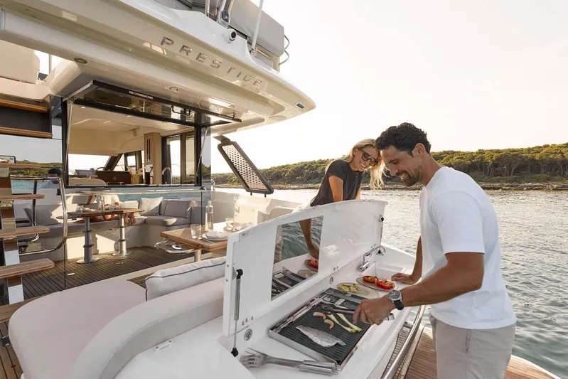  Yacht Photos Pics Manufacturer Provided Image: Couple enjoying barbecue on 2026 Prestige F4.3 yacht, with scenic ocean backdrop.