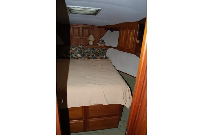 2 Jay's Yacht Photos Pics Cozy bedroom in 1988 Viking 45 Convertible yacht with wooden cabinets and patterned pillows.