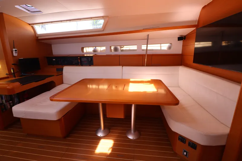 Marley 2 Yacht Photos Pics Interior of 2012 Jeanneau Sun Odyssey 509 yacht with wooden table and white seating.