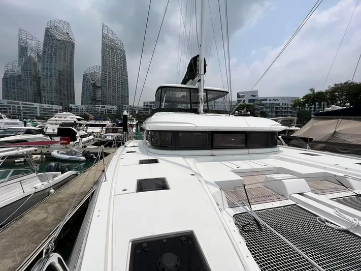 Yacht Photos Pics 2023 Lagoon 55 yacht docked at a marina with modern buildings in the background.
