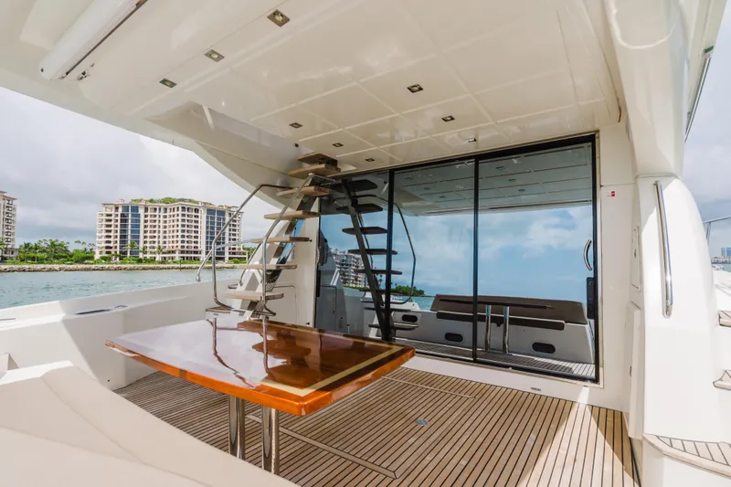 Worldwide Yacht Photos Pics Luxury yacht deck with wooden table, glass doors, and staircase; Prestige 620 Fly, 2014 model.