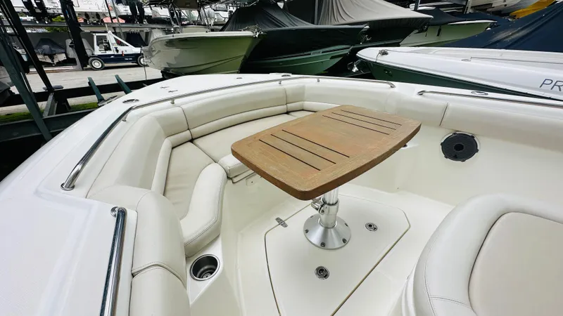  Yacht Photos Pics 2020 Boston Whaler 330 Outrage boat interior with cushioned seating and wooden table.