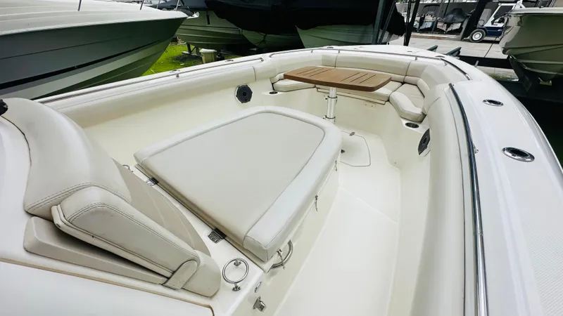  Yacht Photos Pics 2020 Boston Whaler 330 Outrage boat interior with cushioned seating and wooden table.