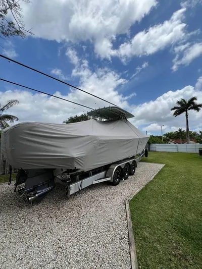  Yacht Photos Pics 2024 Contender 35 ST boat covered, parked on gravel with a cloudy sky backdrop.