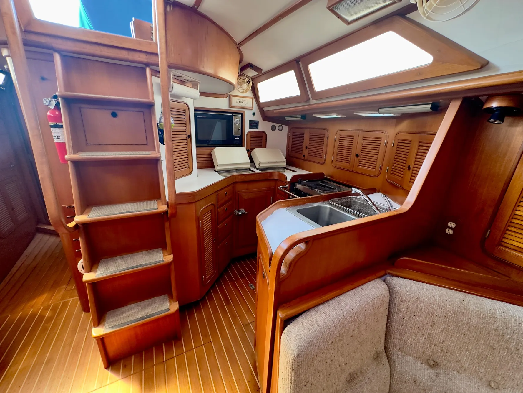 Interior of 1983 Norseman 447 CC Cutter, featuring wooden cabinetry and compact kitchen area.