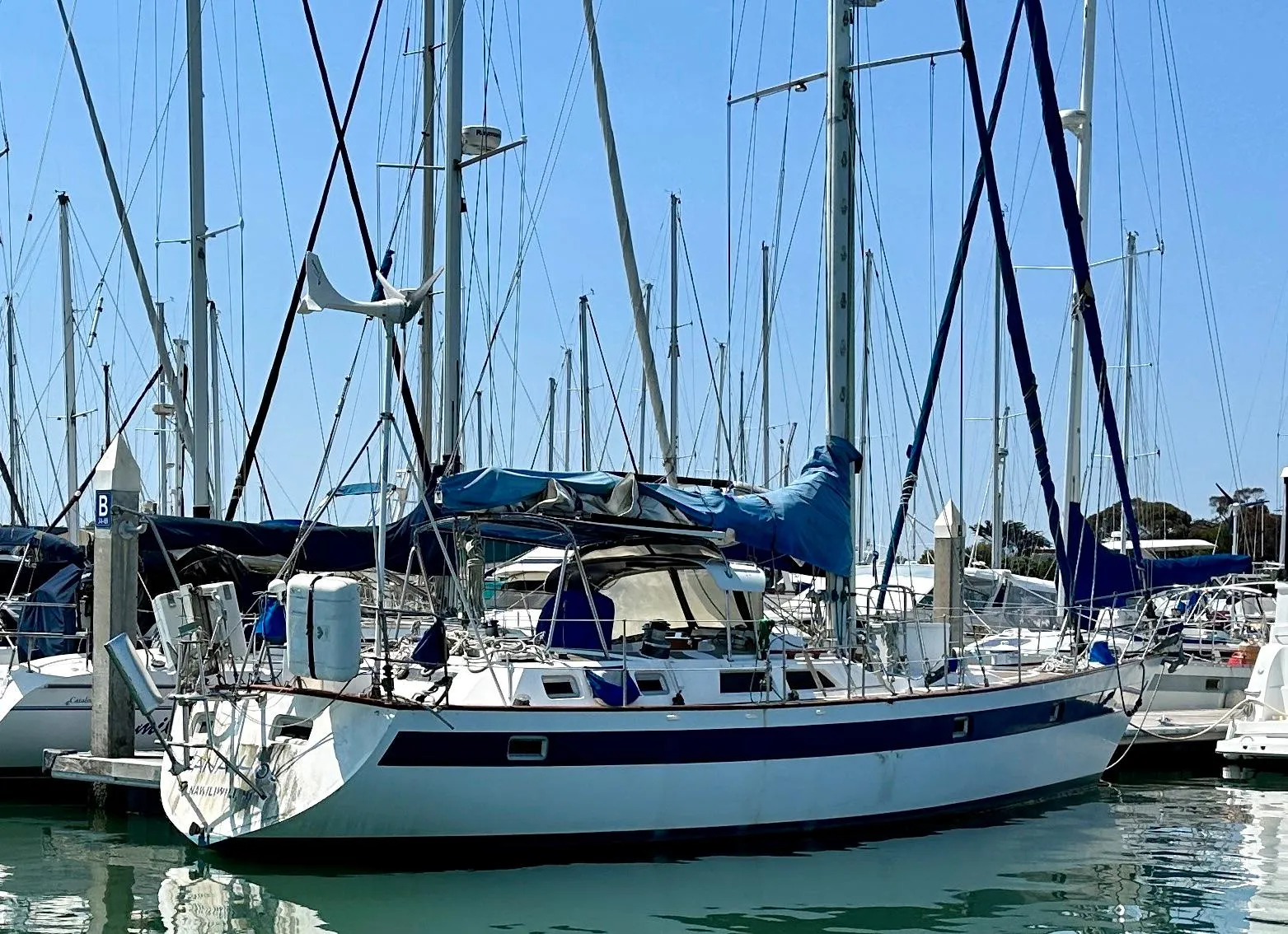 1983 Norseman 447 CC Cutter sailboat docked in a marina, surrounded by other boats.
