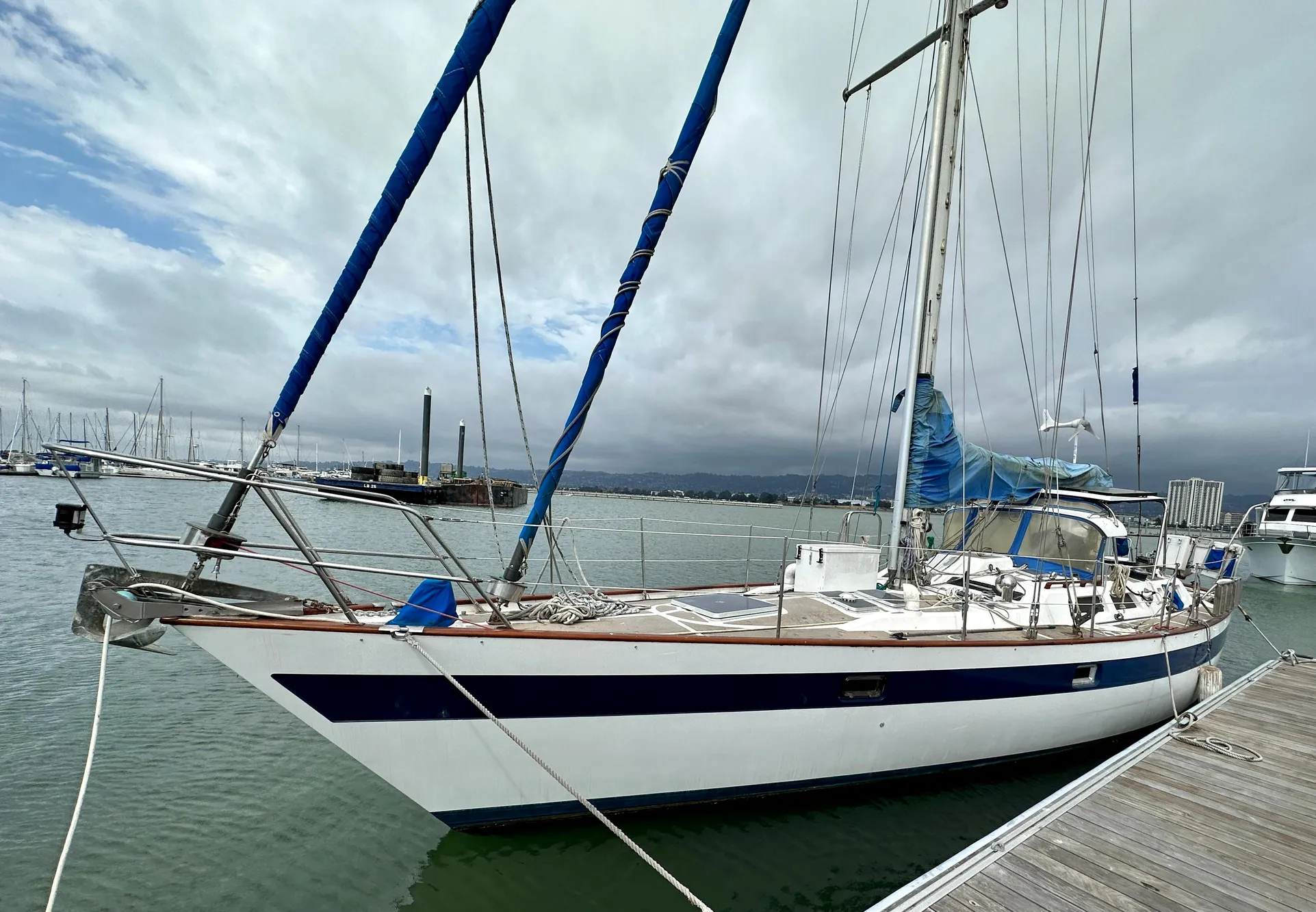 1983 Norseman 447 CC Cutter sailboat docked in a marina under cloudy skies.