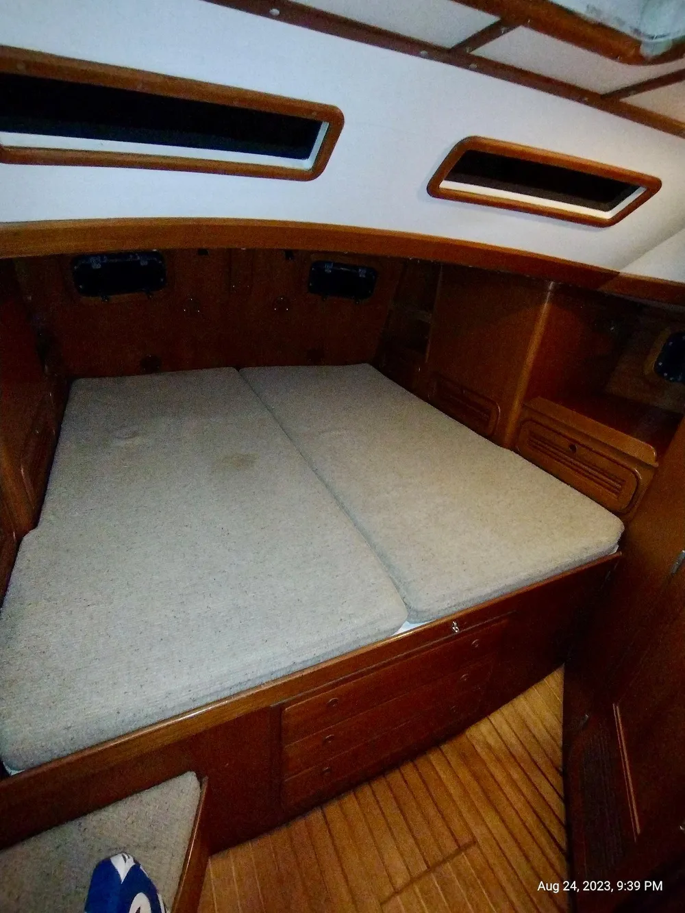 Interior cabin of 1983 Norseman 447 CC Cutter with wooden finish and cozy bedding.