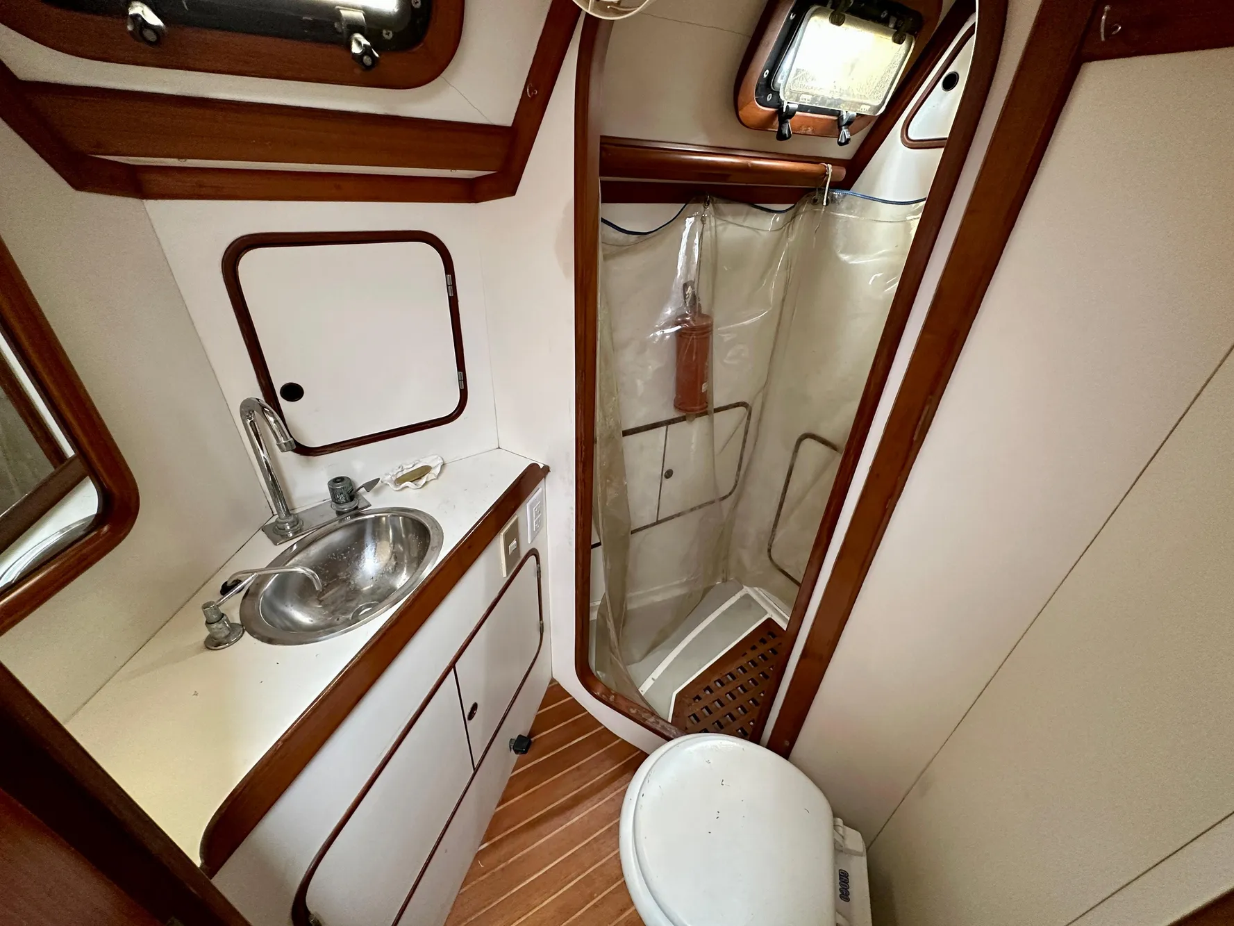 1983 Norseman 447 CC Cutter bathroom with sink, shower, and toilet, featuring wood accents.