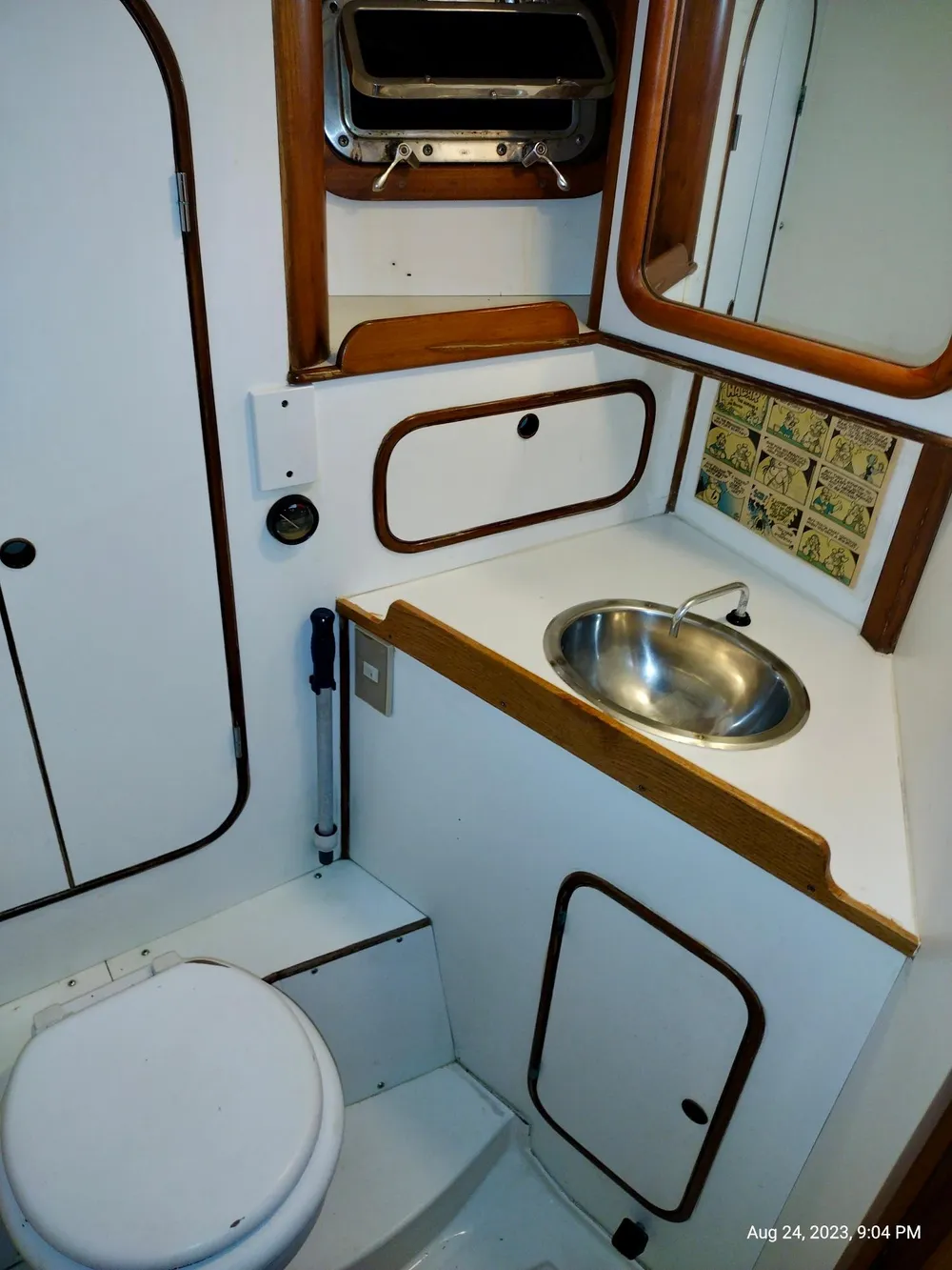 1983 Norseman 447 CC Cutter bathroom with sink, toilet, and storage cabinets.