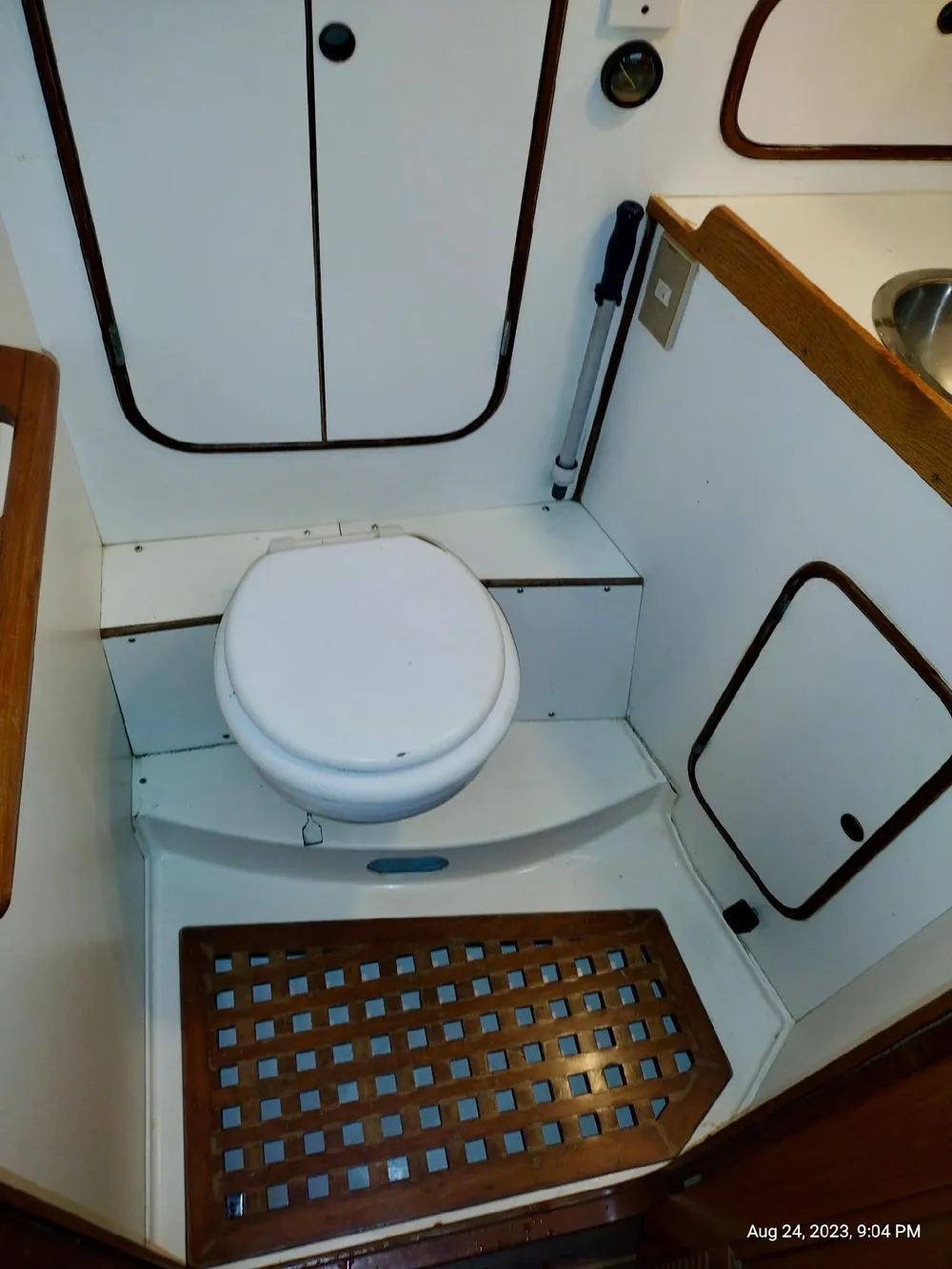 1983 Norseman 447 CC Cutter bathroom with white toilet and wooden accents.