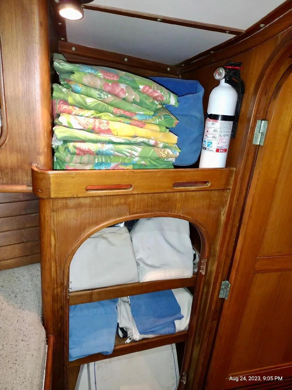 Wooden cabinet in 1983 Norseman 447 CC Cutter with linens and fire extinguisher.