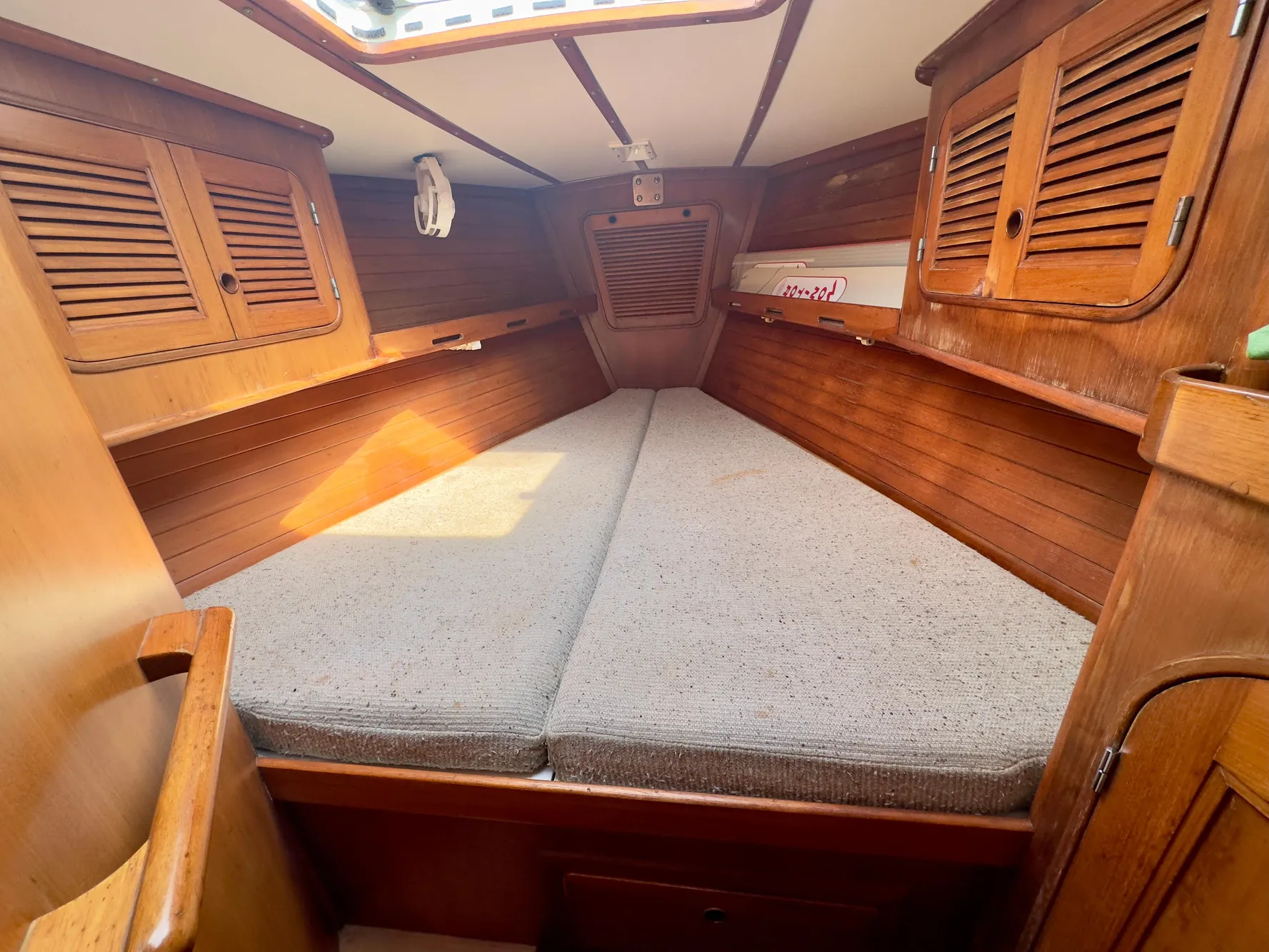 1983 Norseman 447 CC Cutter cabin interior with wooden finish and cushioned bed.