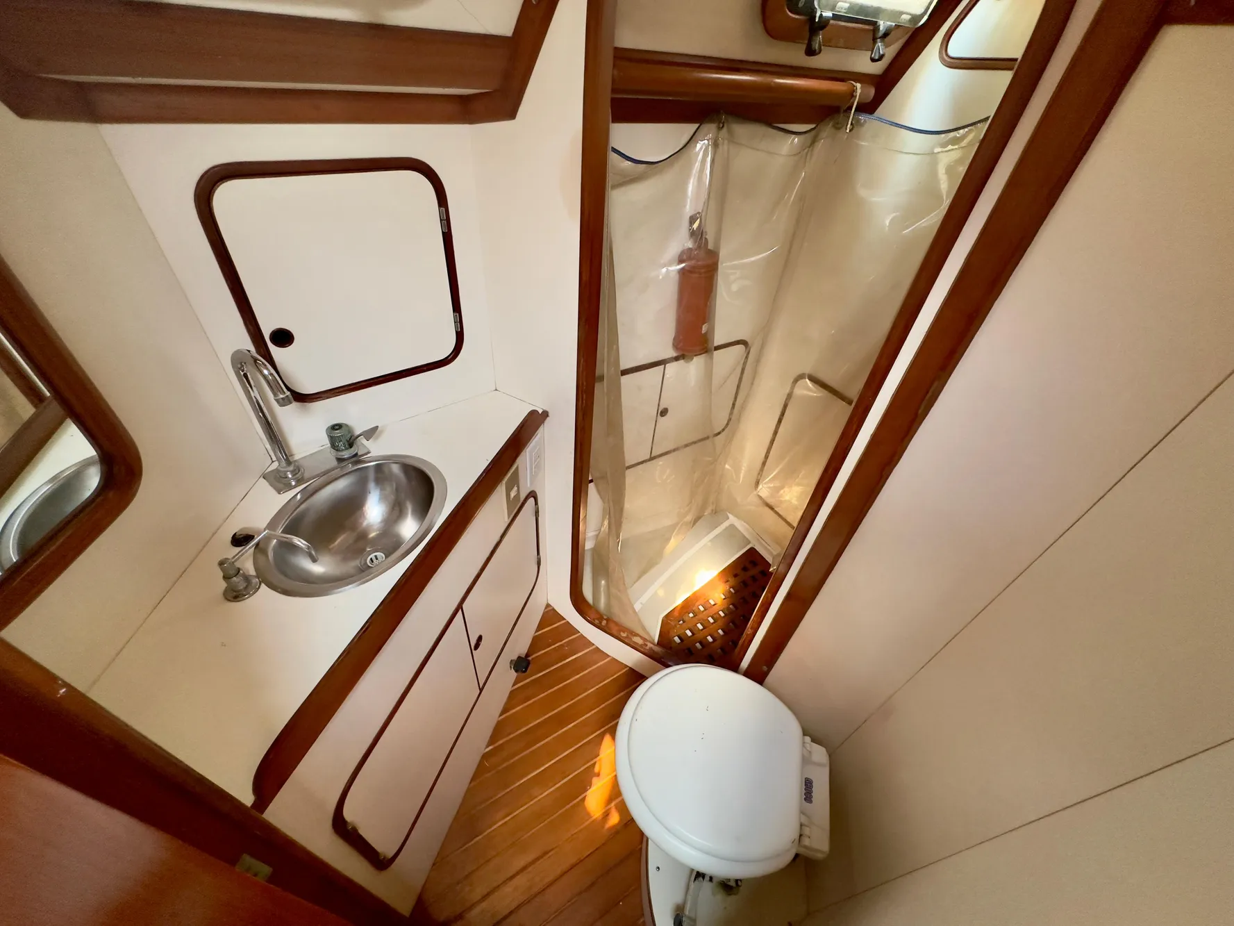 Compact bathroom in 1983 Norseman 447 CC Cutter, featuring sink, toilet, and shower.