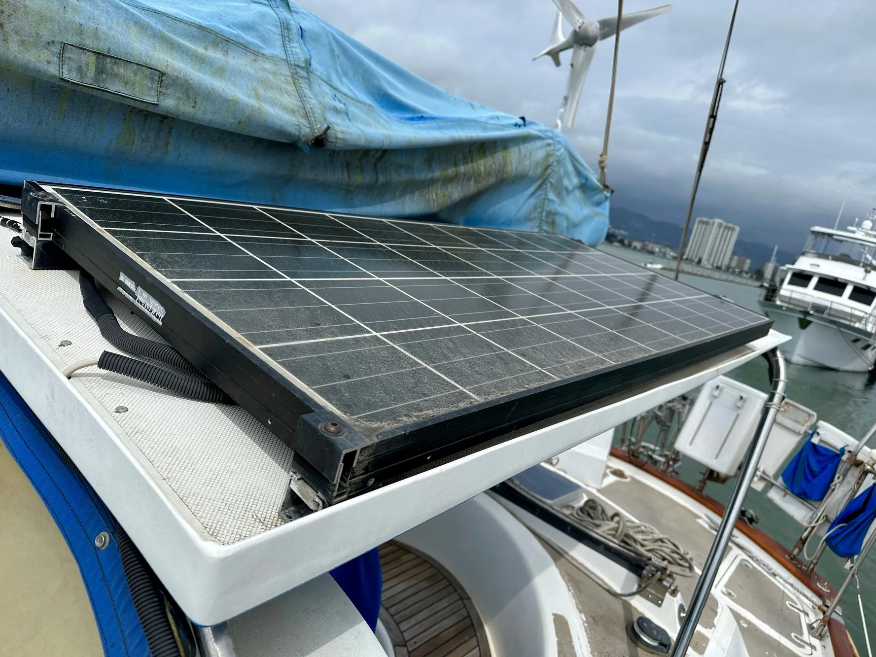 Solar panel on 1983 Norseman 447 CC Cutter sailboat, docked with wind turbine in background.