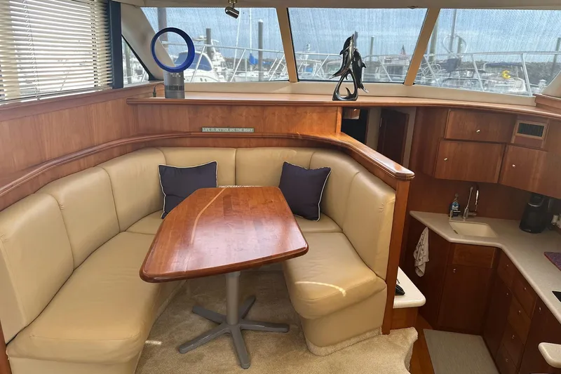 Double Eagle Yacht Photos Pics Interior of 2005 Silverton 42 Convertible yacht with beige seating and wooden table.