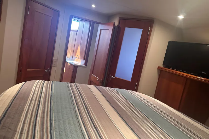 Double Eagle Yacht Photos Pics Interior of 2005 Silverton 42 Convertible yacht bedroom with striped bedding and TV.