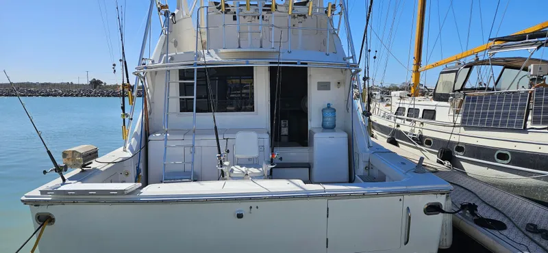 True Grit Yacht Photos Pics 1995 Bertram Convertible yacht docked at marina, rear view with fishing equipment.