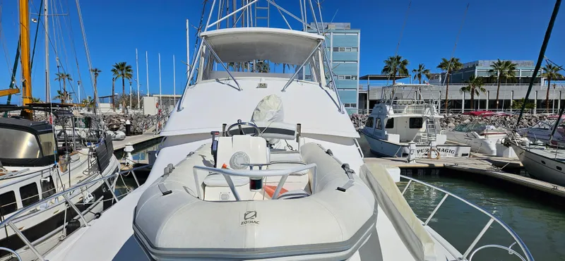 True Grit Yacht Photos Pics 1995 Bertram Convertible yacht docked at marina, featuring inflatable boat on deck.