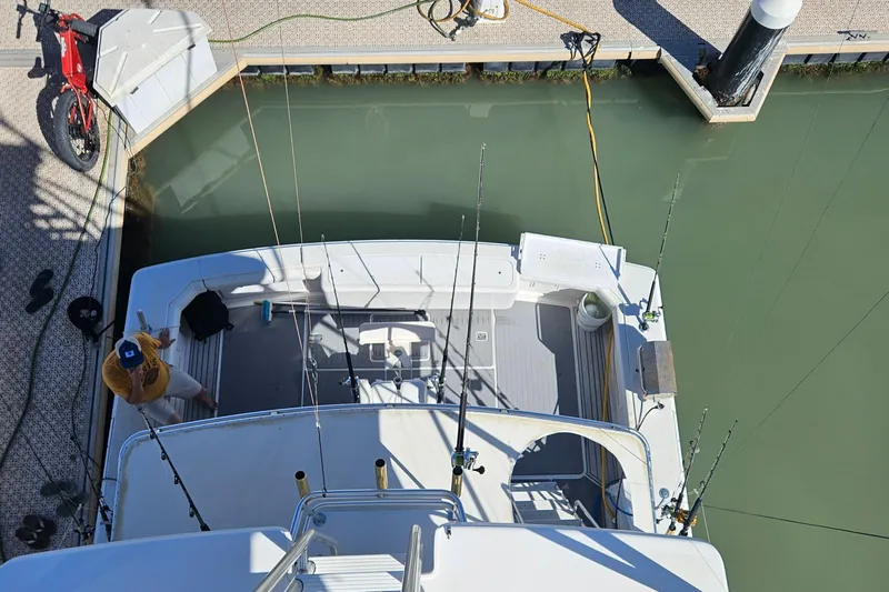 True Grit Yacht Photos Pics 1995 Bertram Convertible boat docked, viewed from above, with fishing rods and a bicycle nearby.