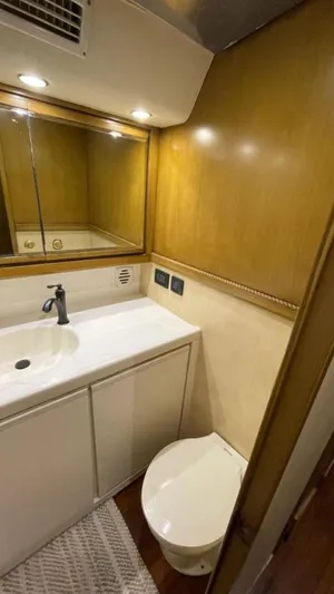 True Grit Yacht Photos Pics 1995 Bertram Convertible yacht bathroom with wooden cabinetry and modern fixtures.