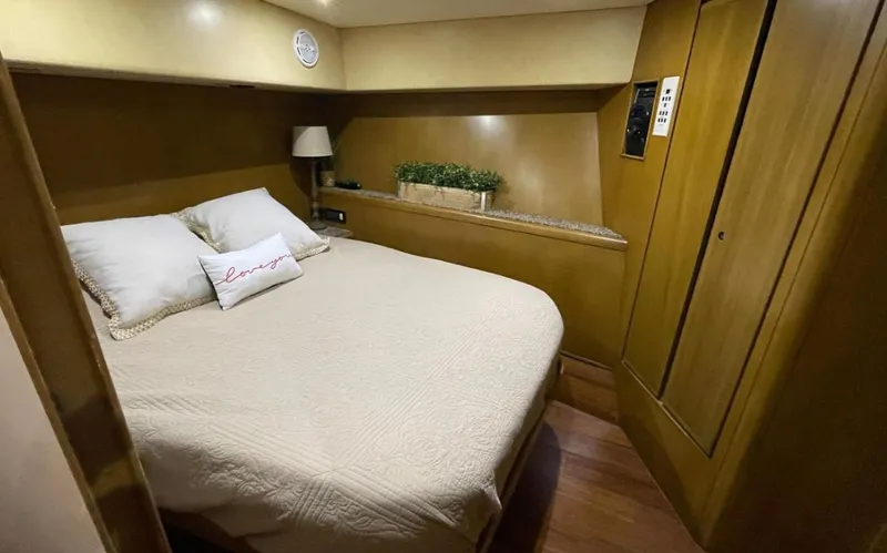 True Grit Yacht Photos Pics 1995 Bertram Convertible yacht bedroom with cozy bed, wooden cabinetry, and soft lighting.