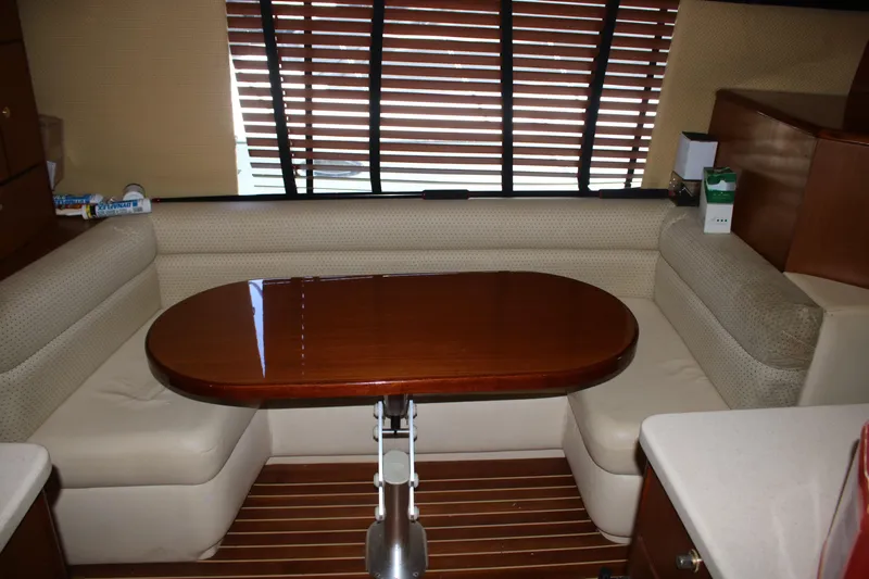 Sweetemocian Yacht Photos Pics Interior of a 1999 Ocean Yachts model, featuring a wooden table and cushioned seating.