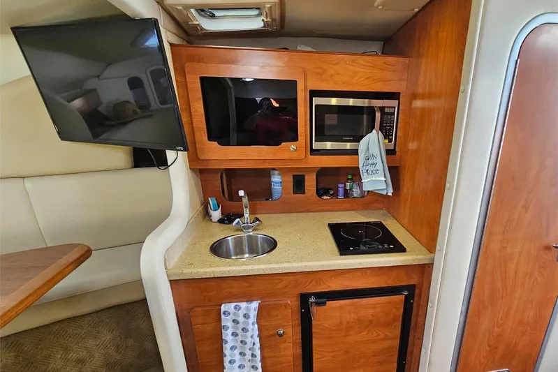 Sabroso Yacht Photos Pics 2006 Rinker 300 Express Cruiser interior kitchen with sink, microwave, and TV.