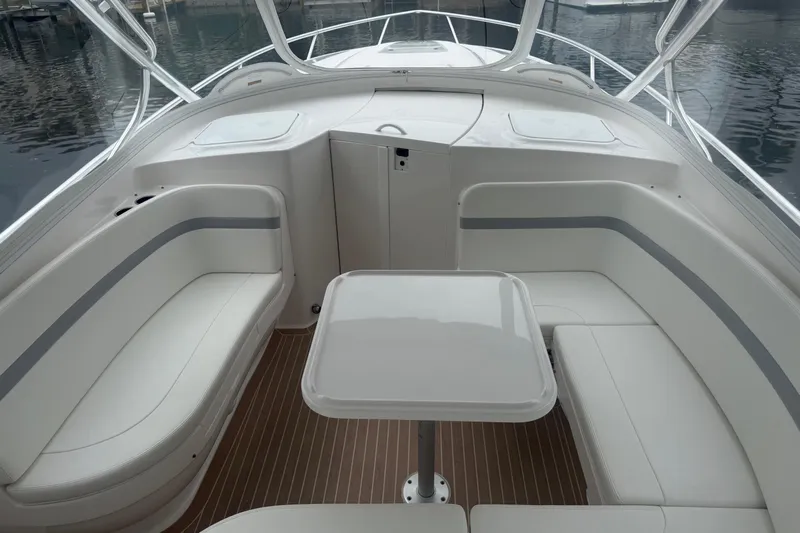 Day Dreams Yacht Photos Pics 2021 Intrepid 409 Valor boat interior with white seating and table, docked on calm water.