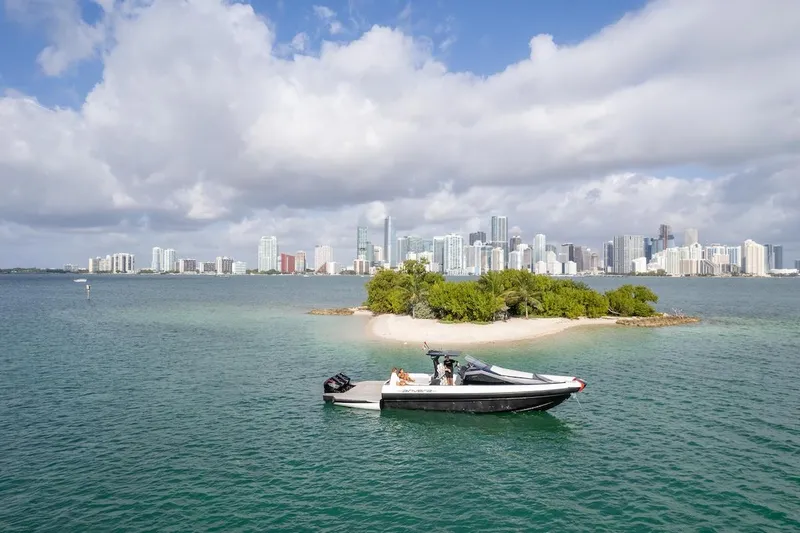  Yacht Photos Pics 2025 Anvera 42 Speedster boat cruising near a small island with city skyline backdrop.