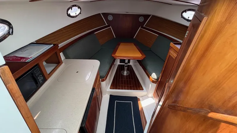 Uncle Ray Yacht Photos Pics 2004 Back Cove 29 interior with kitchenette, seating, and wooden table.