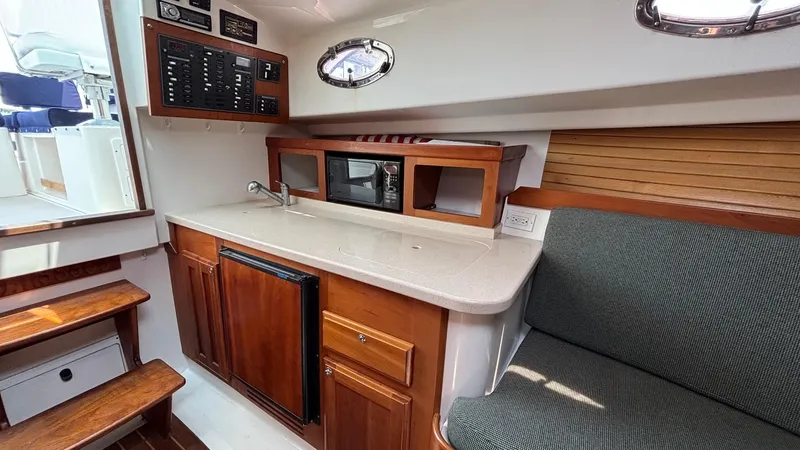 Uncle Ray Yacht Photos Pics 2004 Back Cove 29 interior with kitchenette, wood cabinetry, and seating area.