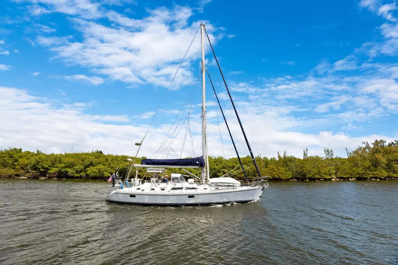Southern Cross Yacht Photos Pics Sailing yacht Hylas 46 (2004) cruising on a sunny day with lush greenery background.