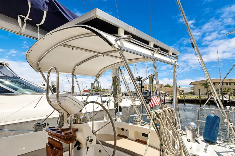 Southern Cross Yacht Photos Pics 2004 Hylas 46 sailboat cockpit with steering wheel, ropes, and American flag in marina.