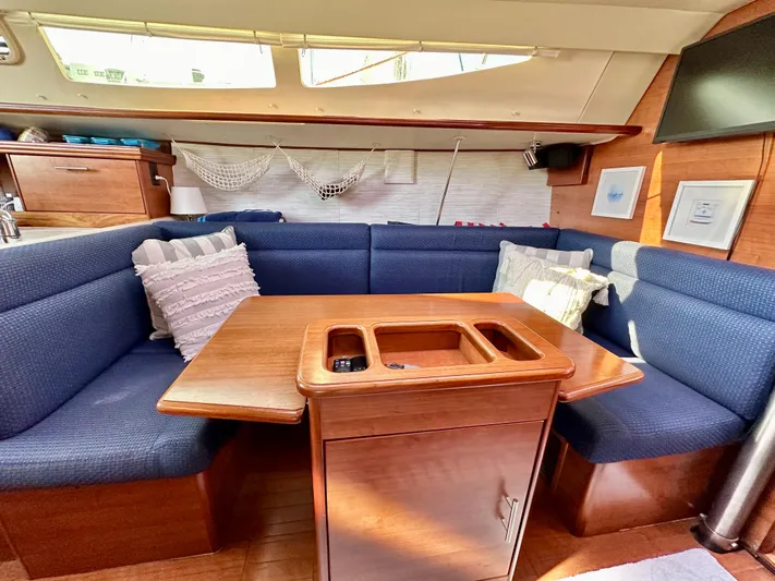 To The Gills Yacht Photos Pics Cozy interior of 2014 Hunter 33 sailboat with blue seating and wooden table.