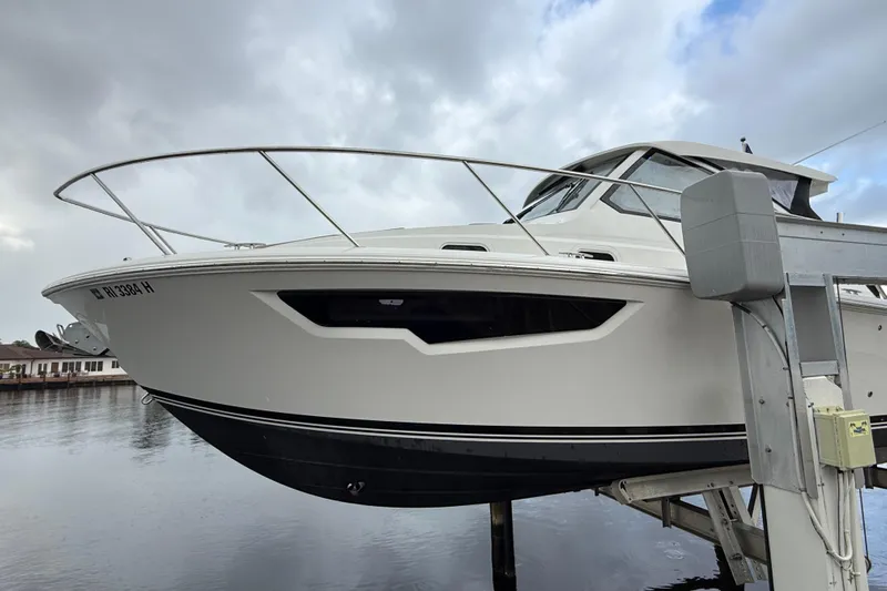  Yacht Photos Pics 2025 Pursuit OS 325 Offshore boat on lift, cloudy sky background.