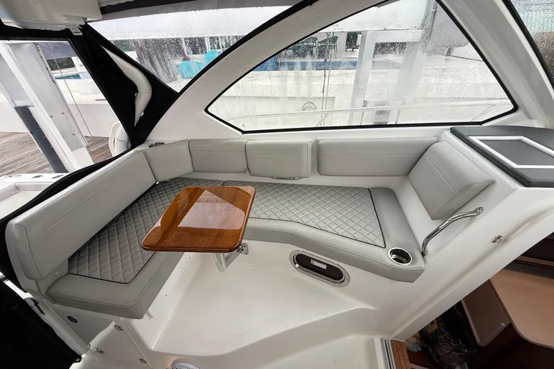  Yacht Photos Pics 2025 Pursuit OS 325 Offshore boat interior with cushioned seating and wooden table.